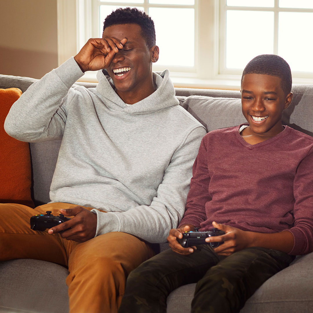 father and son playing video games on the couch